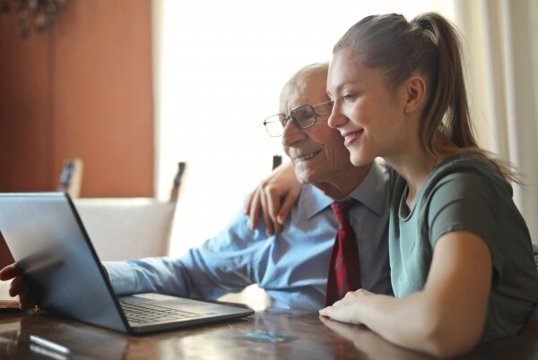 young-positive-woman-helping-senior-man-using-laptop-3823489